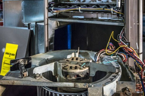 Man in workwear inspecting a furnace in a basement.