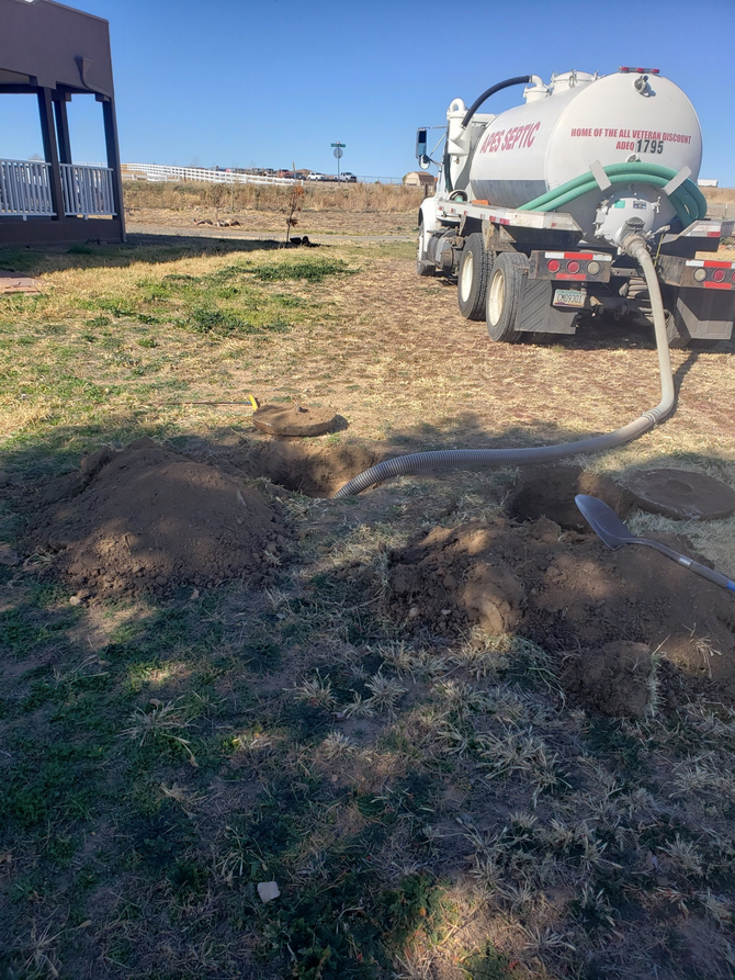 A vacuum truck is pumping water into a hole in the ground.