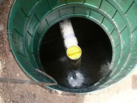 A green septic tank with a yellow cap and a pipe in it.