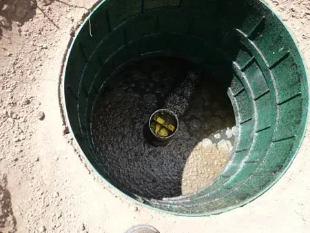 The inside of a green barrel filled with dirt and water.