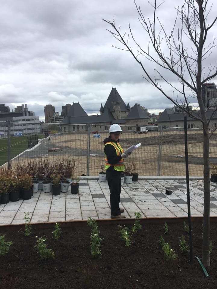Une femme portant un casque et un gilet de sécurité est debout dans un jardin