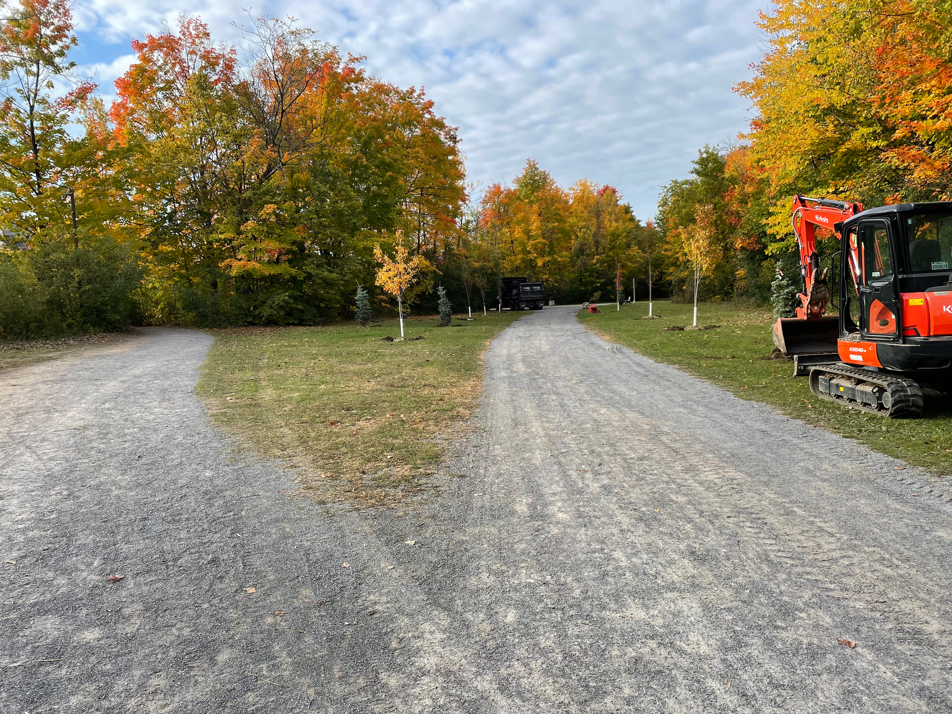 Une route de gravier avec un tracteur à côté.