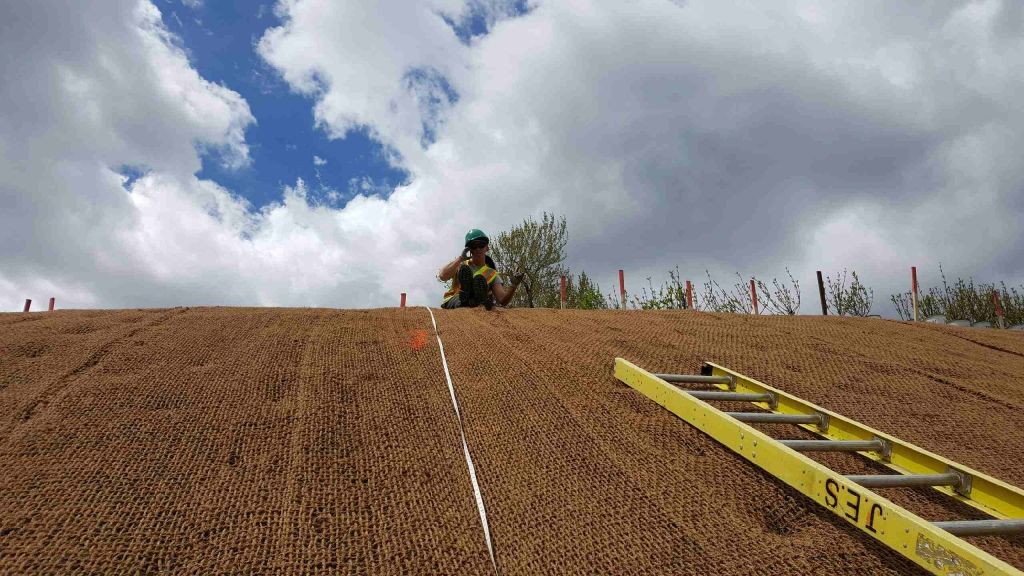 Une personne se tient au sommet d’une colline de terre, à côté d’une échelle.