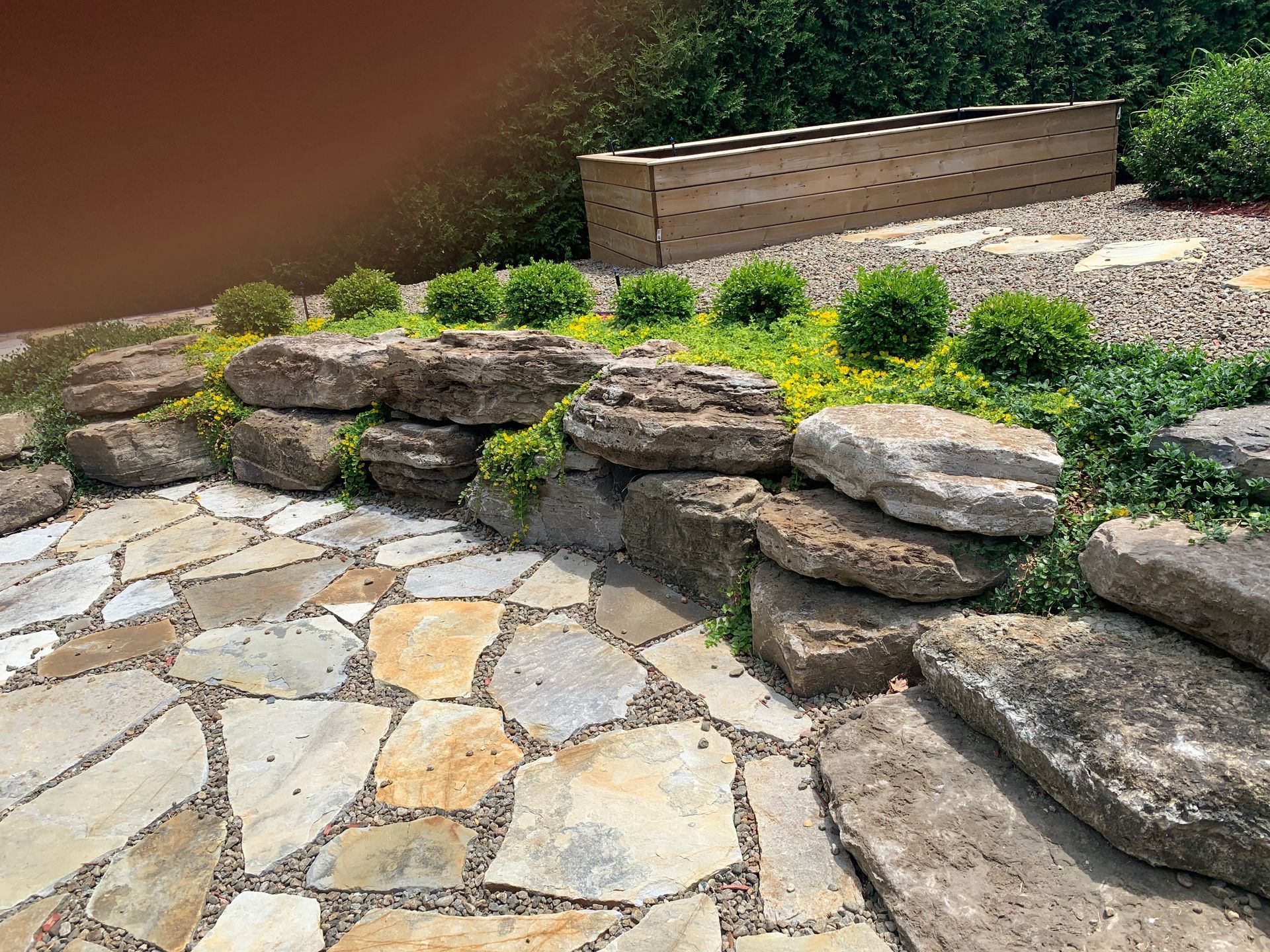 Une passerelle en pierre entourée de rochers et de plantes dans un jardin.