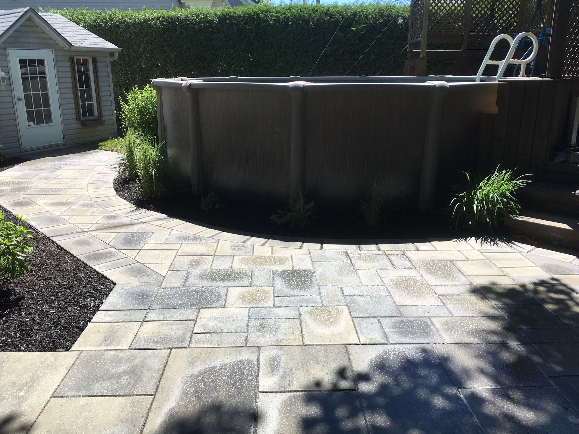 Une piscine est située au sommet d'un patio à côté d'un cabanon.