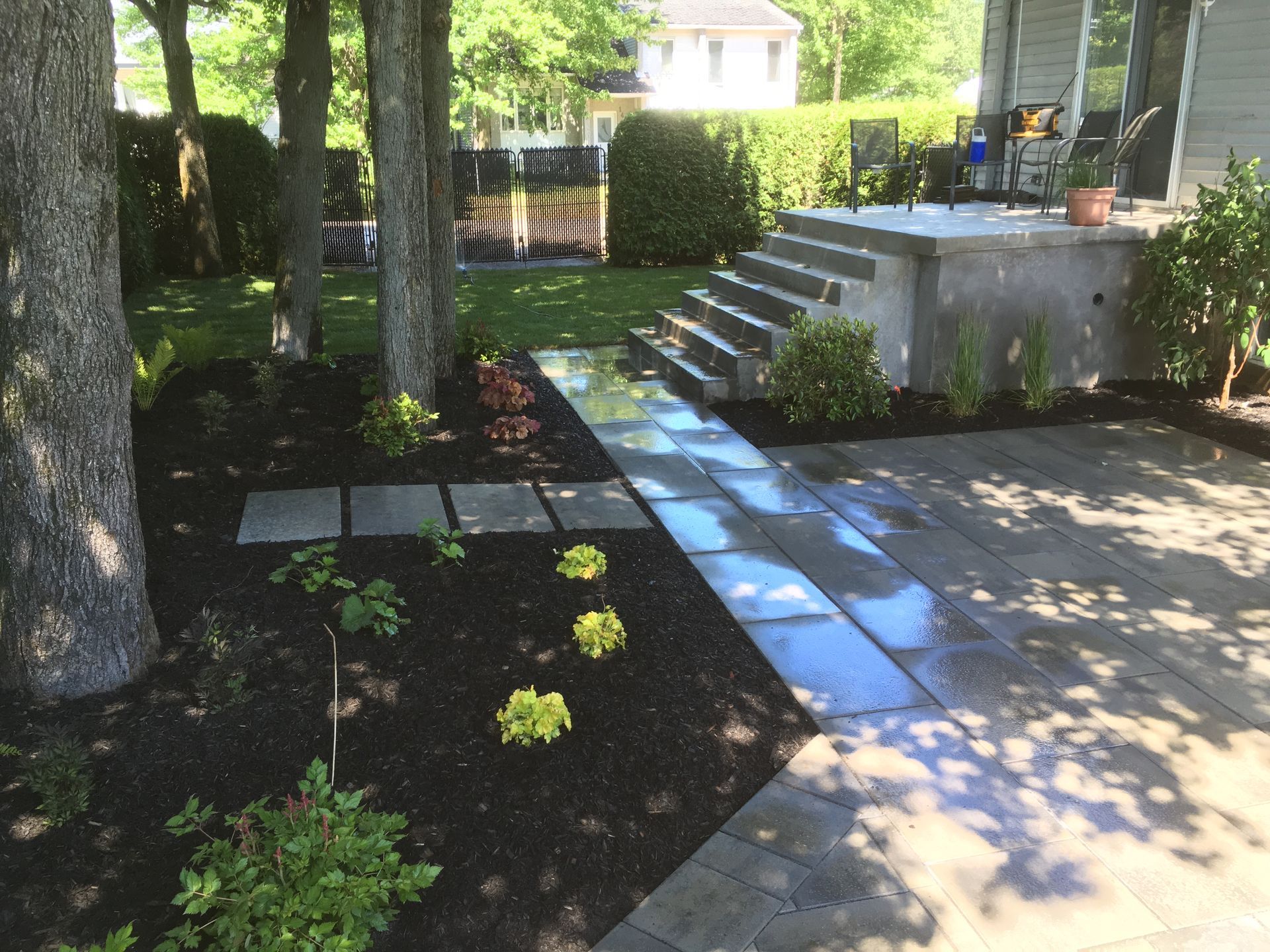 Un patio avec des marches menant à un porche et des arbres en arrière-plan