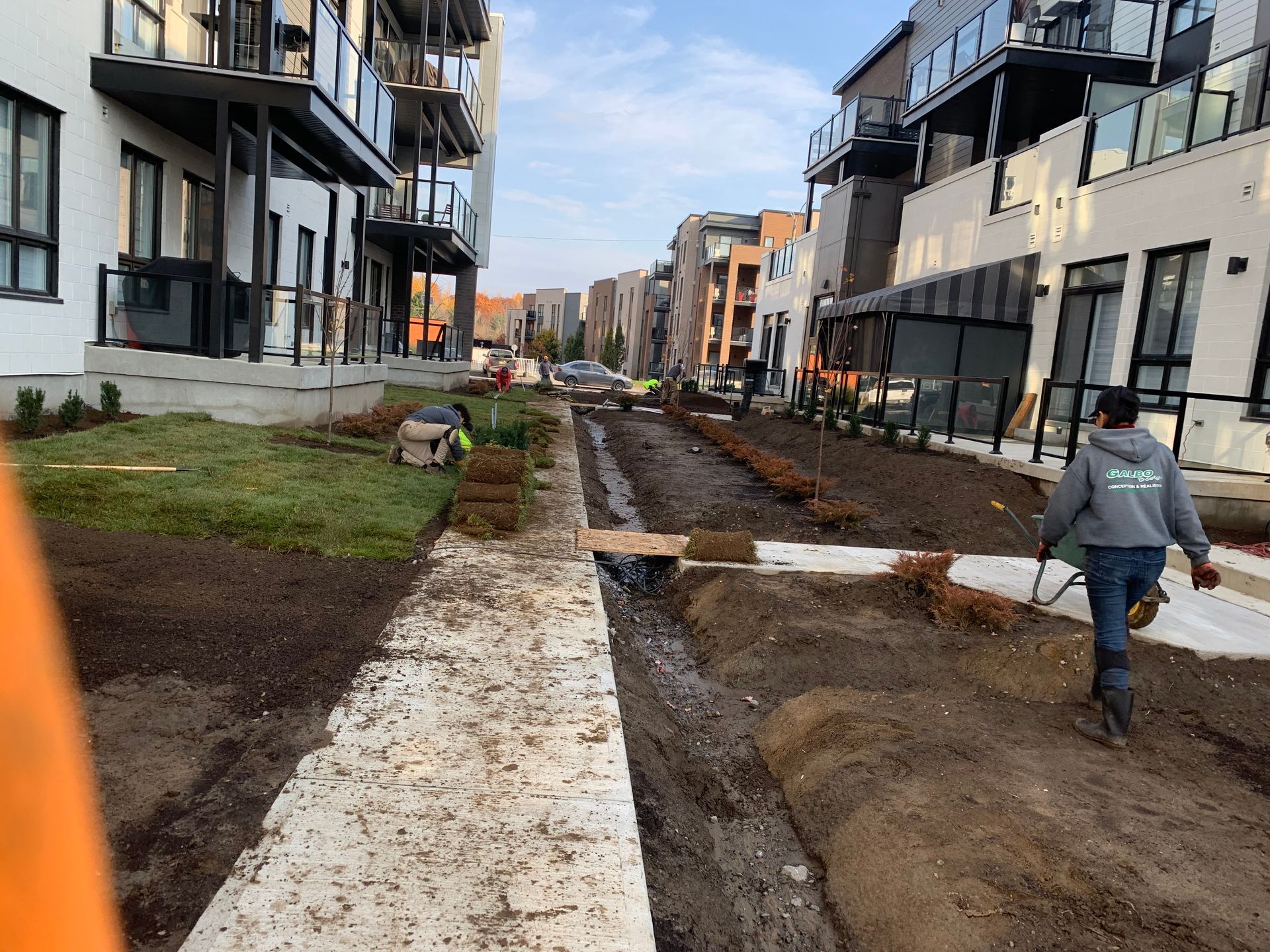 Un homme marche sur un chemin de terre devant un immeuble.