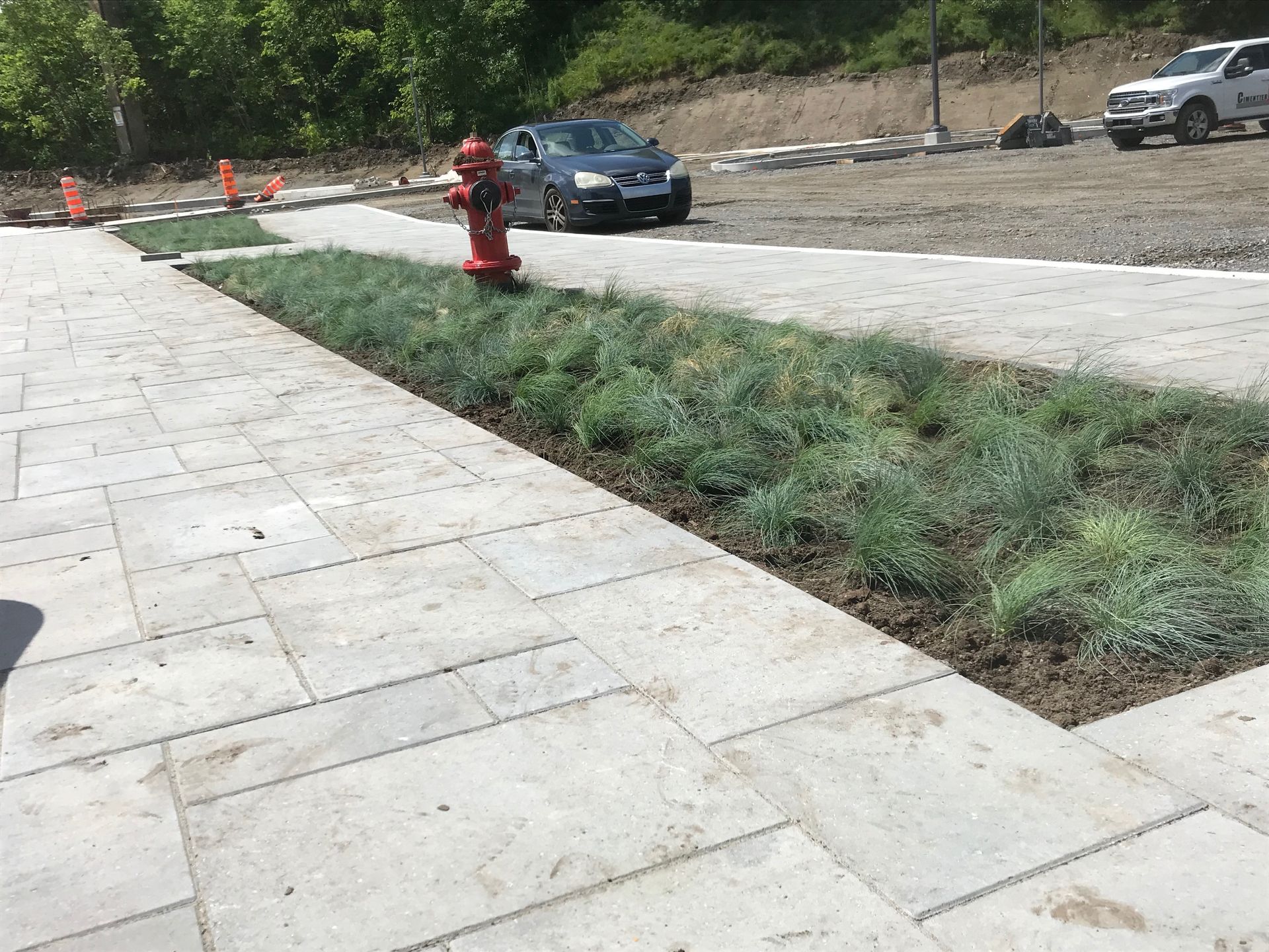 Une bouche d'incendie se trouve au milieu d'un trottoir à côté d'une voiture.