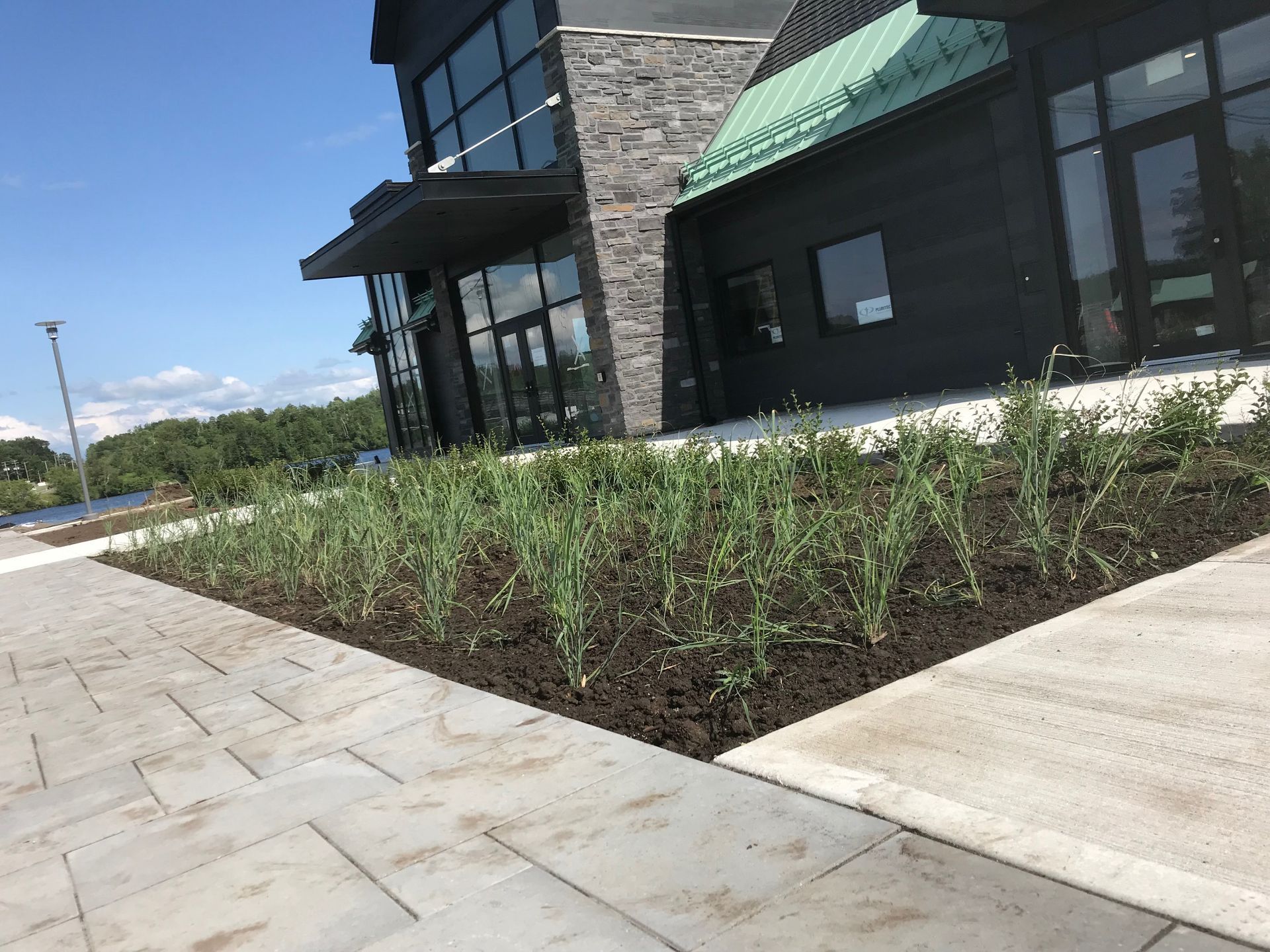 Un bâtiment avec un auvent vert est entouré d'un jardin verdoyant.
