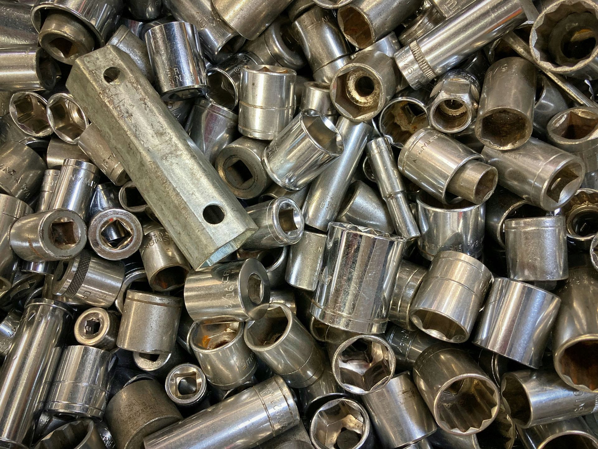A pile of shiny metal sleeves and bolts scattered in a heap