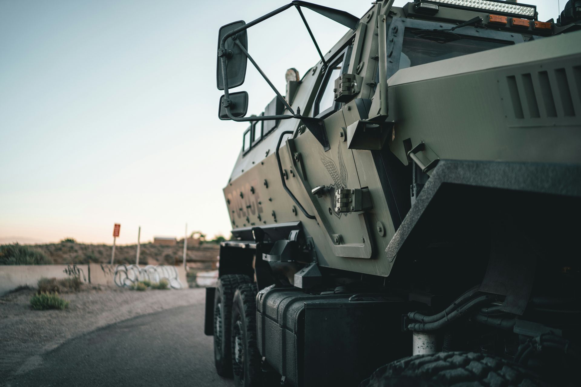 Heavy tracked construction machine parked on a road at sunset, with a large crane boom visible.