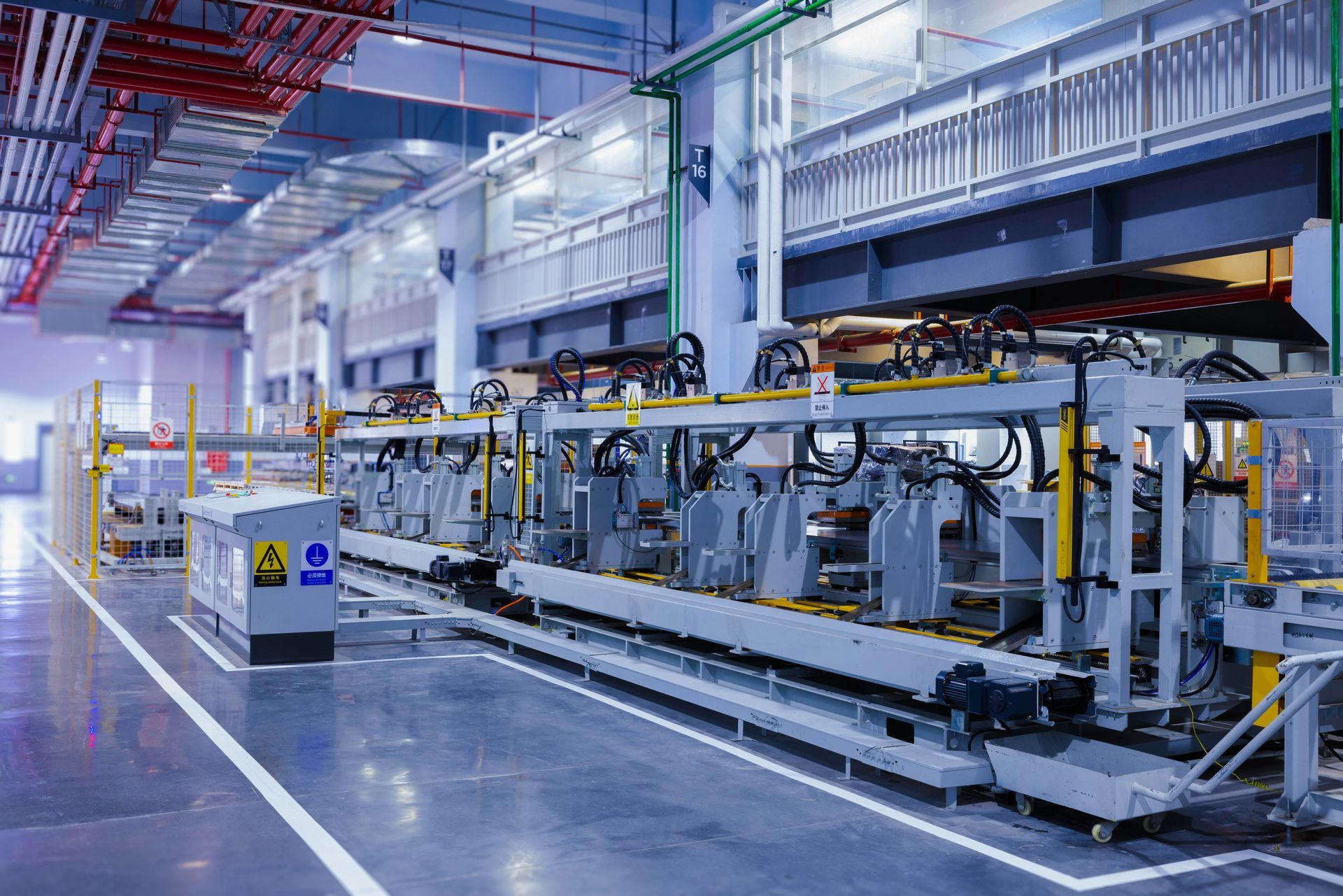 Automated factory assembly line with yellow machinery and overhead rails in a clean industrial interior