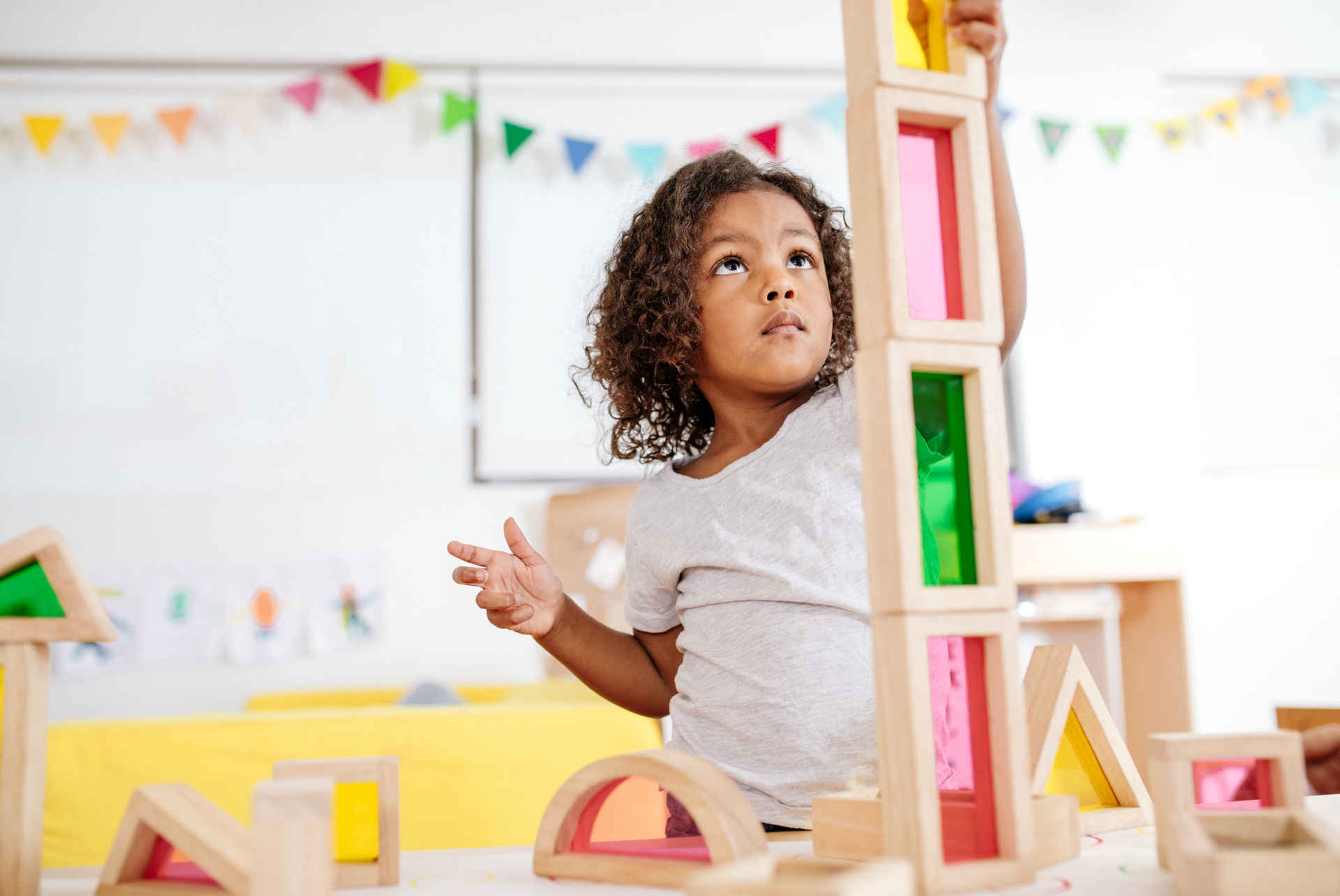 A little girl is playing with wooden blocks in a classroom.