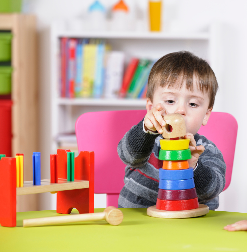 A little boy is sitting at a table playing with wooden toys