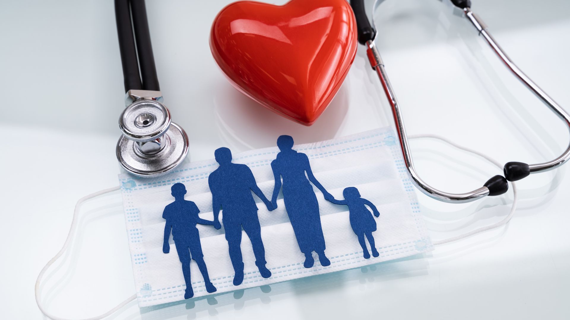 Blue family silhouettes under a red heart beside a stethoscope on a clipboard