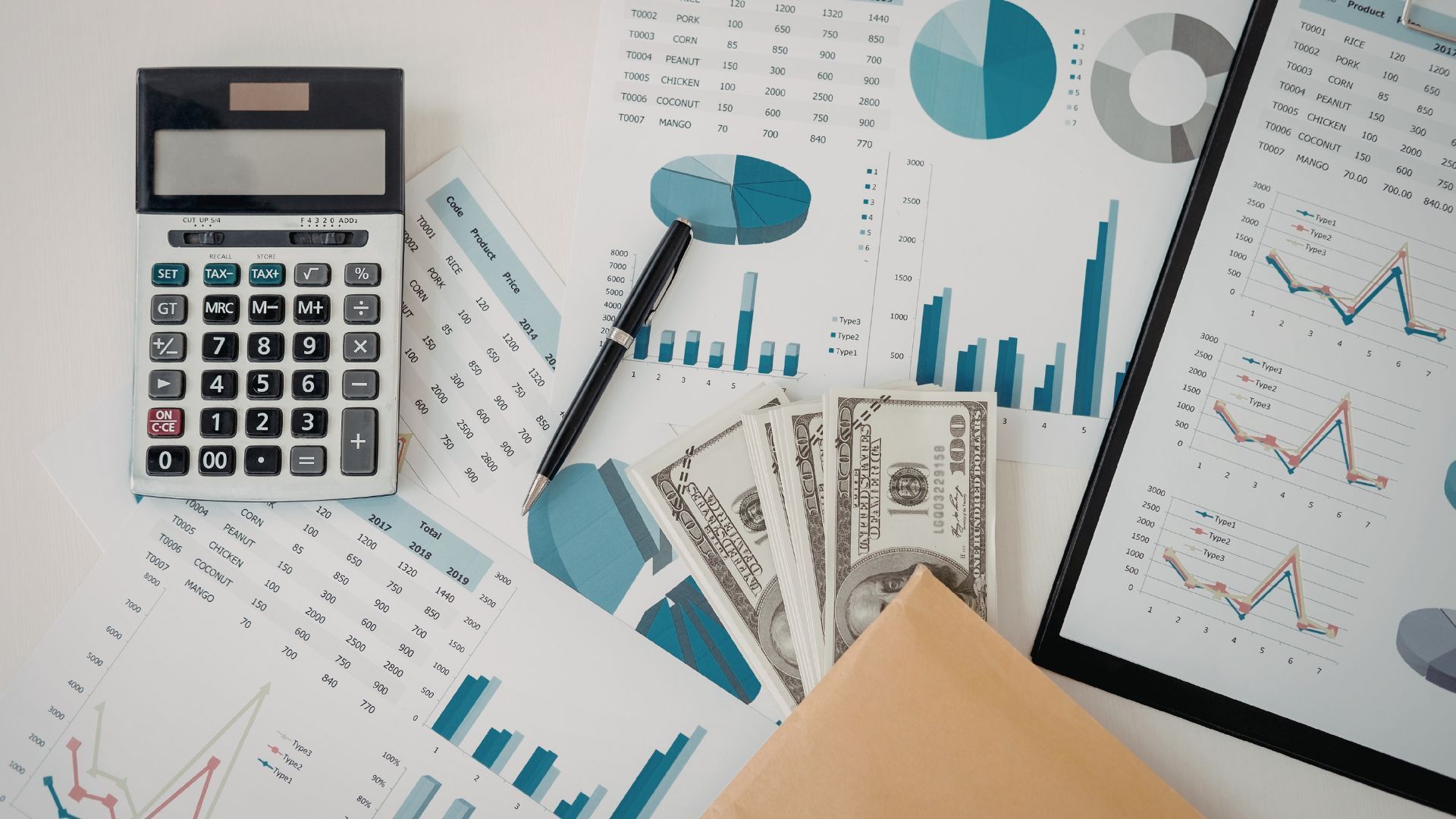Calculator, charts, and scattered financial papers with blue graphs and cash on a desk