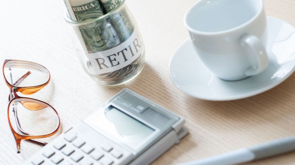 Glasses, calculator, retirement jar, and white cup on a desk