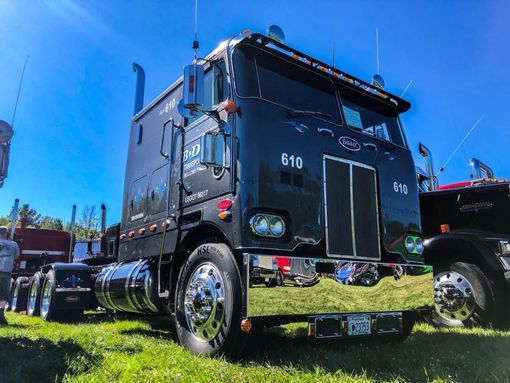 A black semi truck is parked in a grassy field.