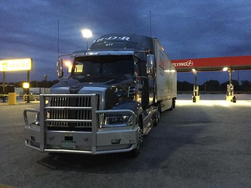 A semi truck is parked in front of a gas station