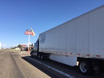 A semi truck is parked in front of a cafe sign