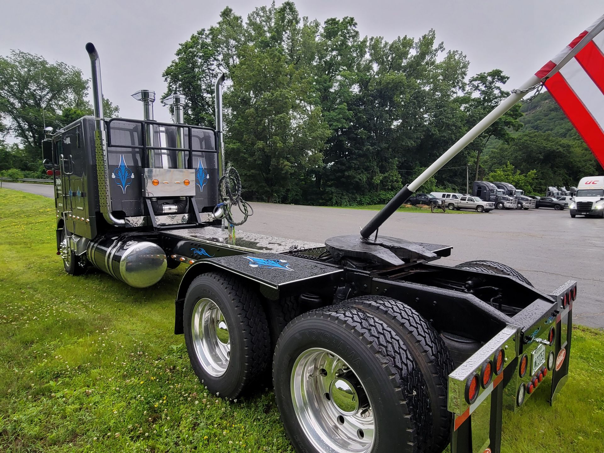 A semi truck with a trailer attached to it is parked in a grassy field.