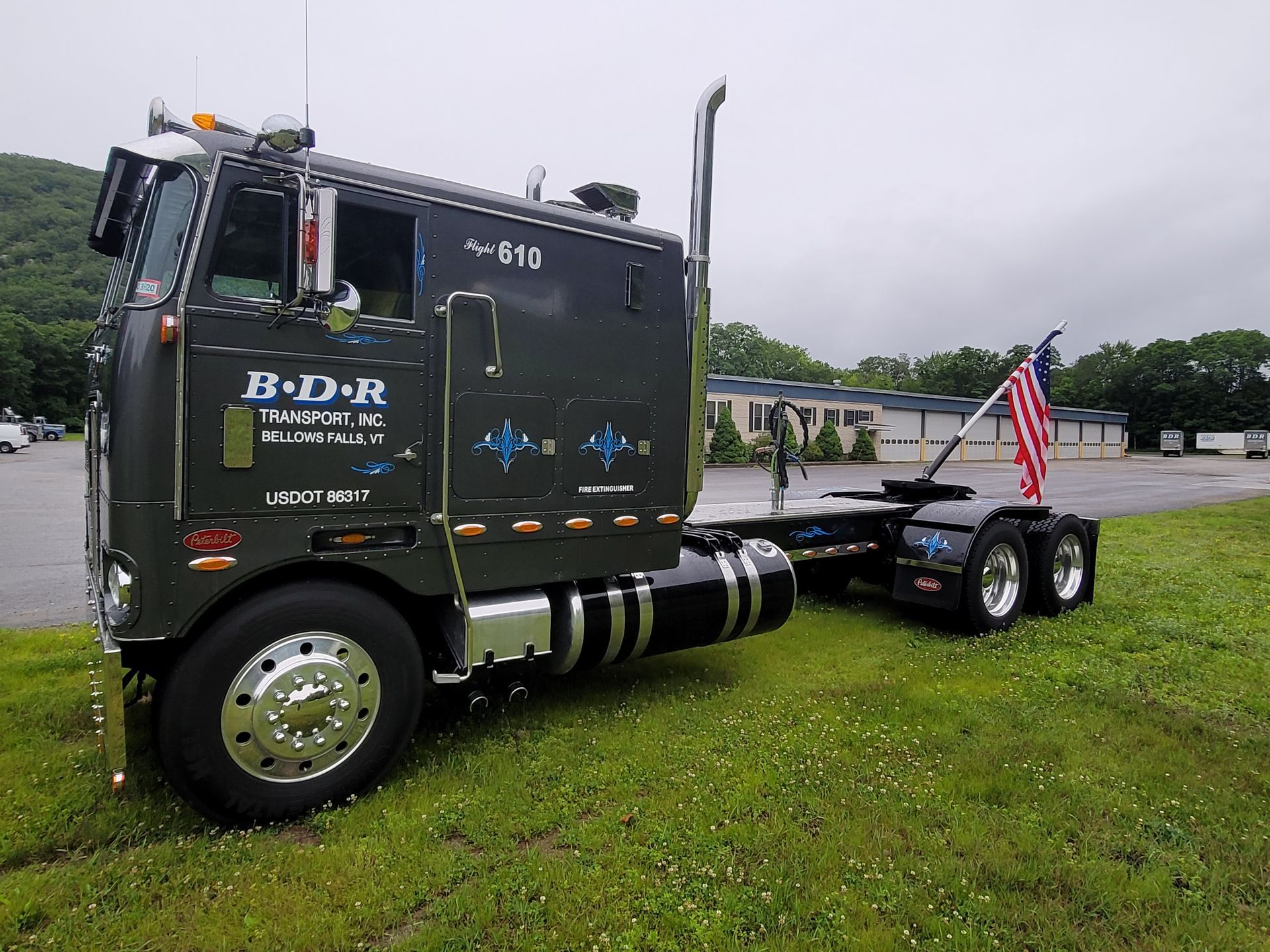 A black semi truck is parked in a grassy field.