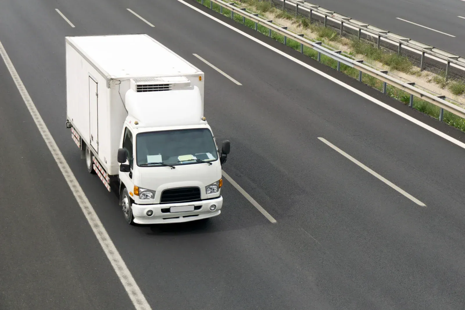 A green semi truck is driving down a highway.