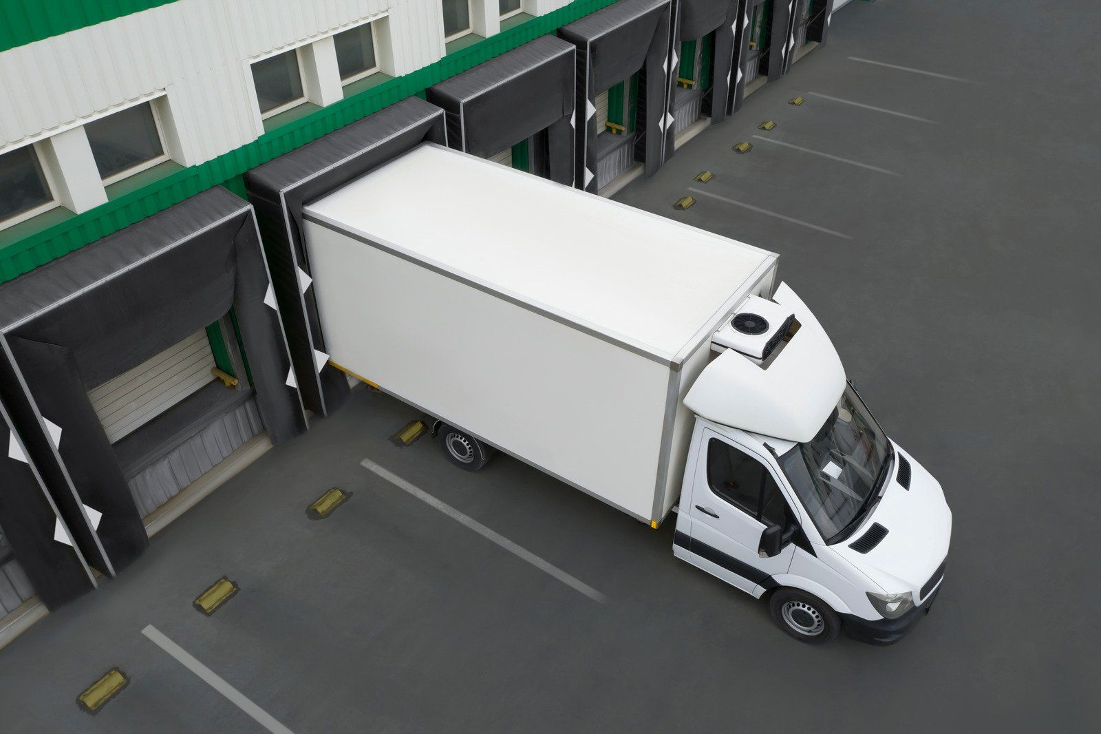 A white truck is parked in front of a warehouse.