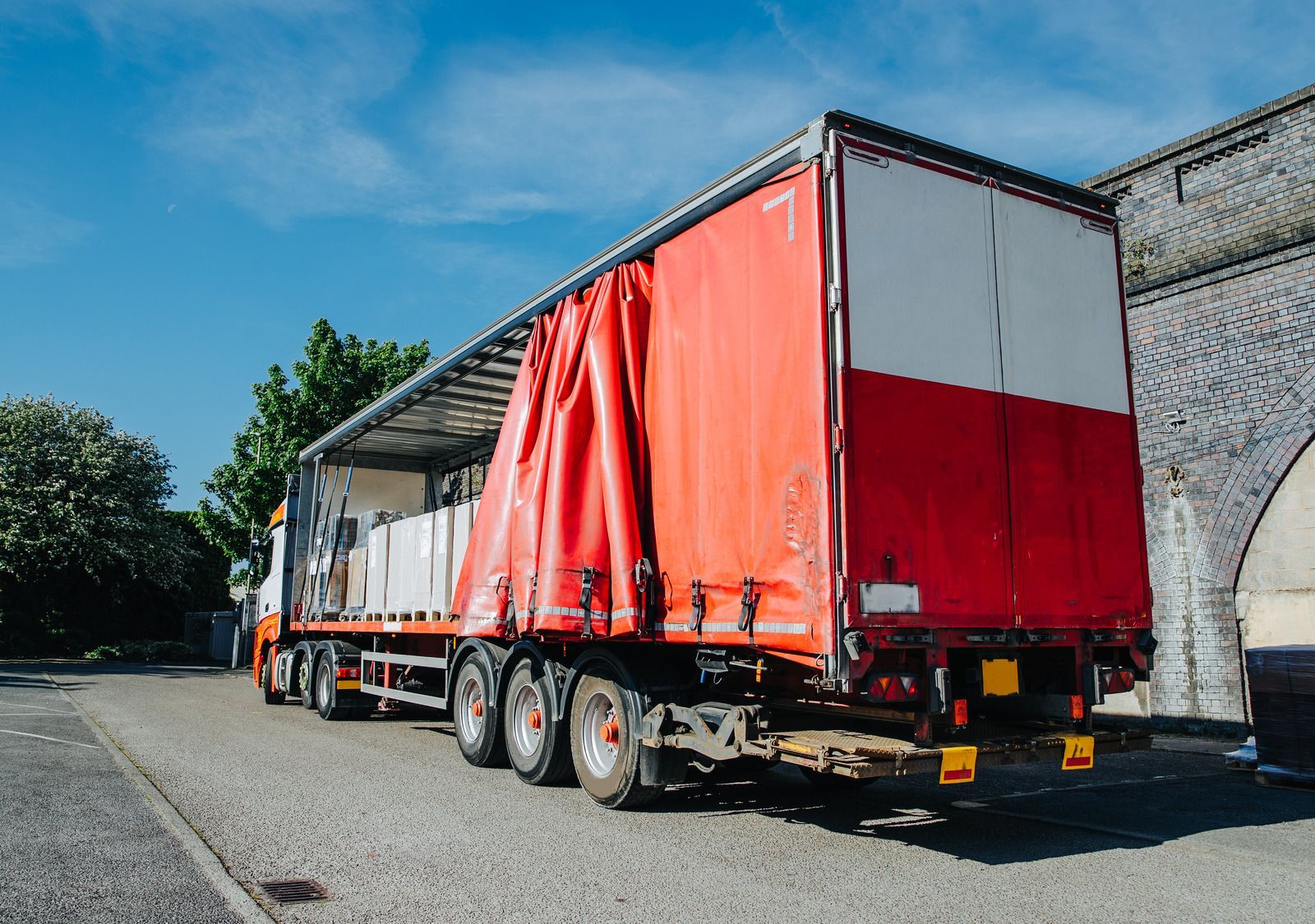 A red and white semi truck is parked on the side of the road.