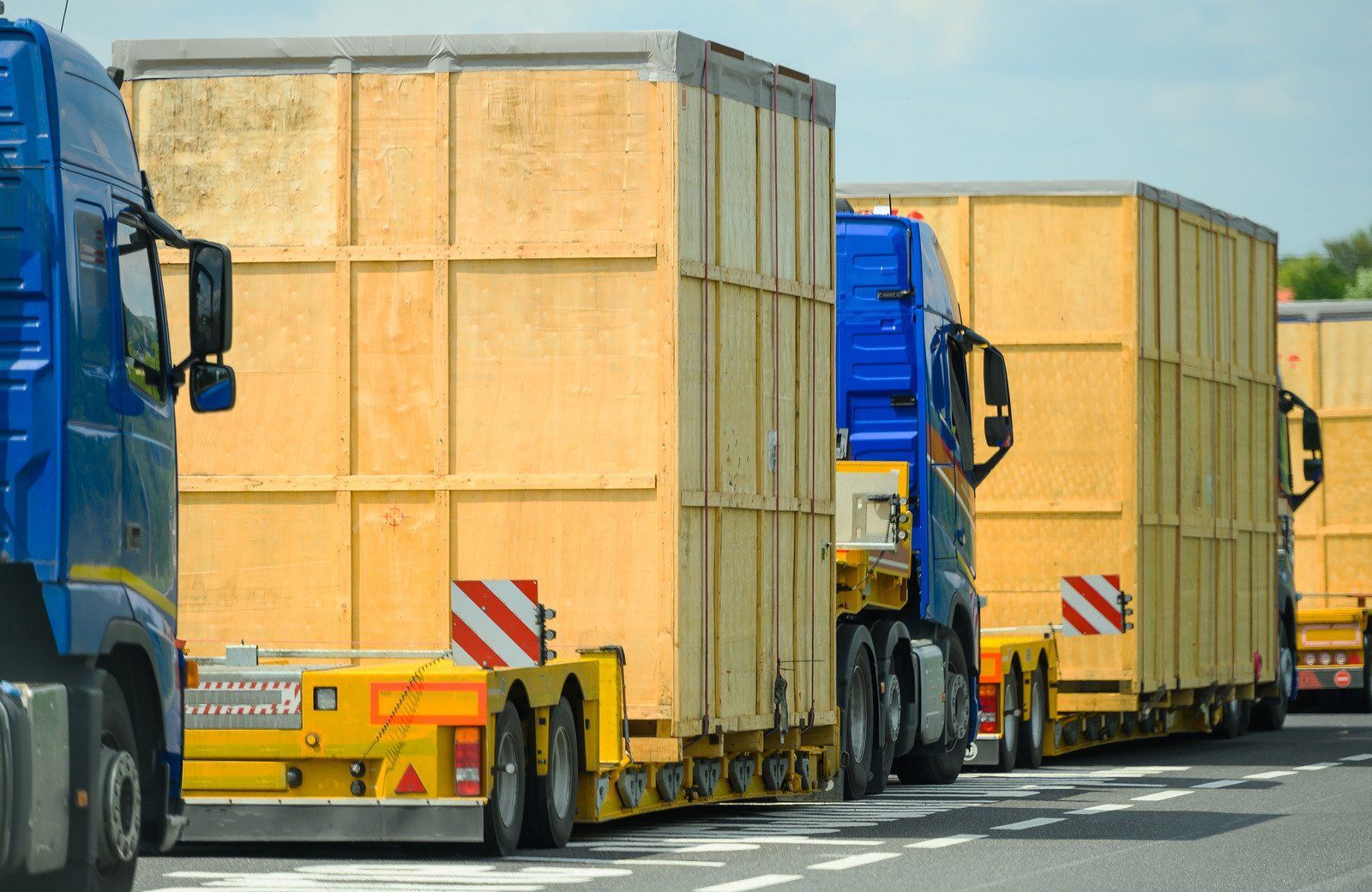 A row of trucks carrying wooden crates on a highway.