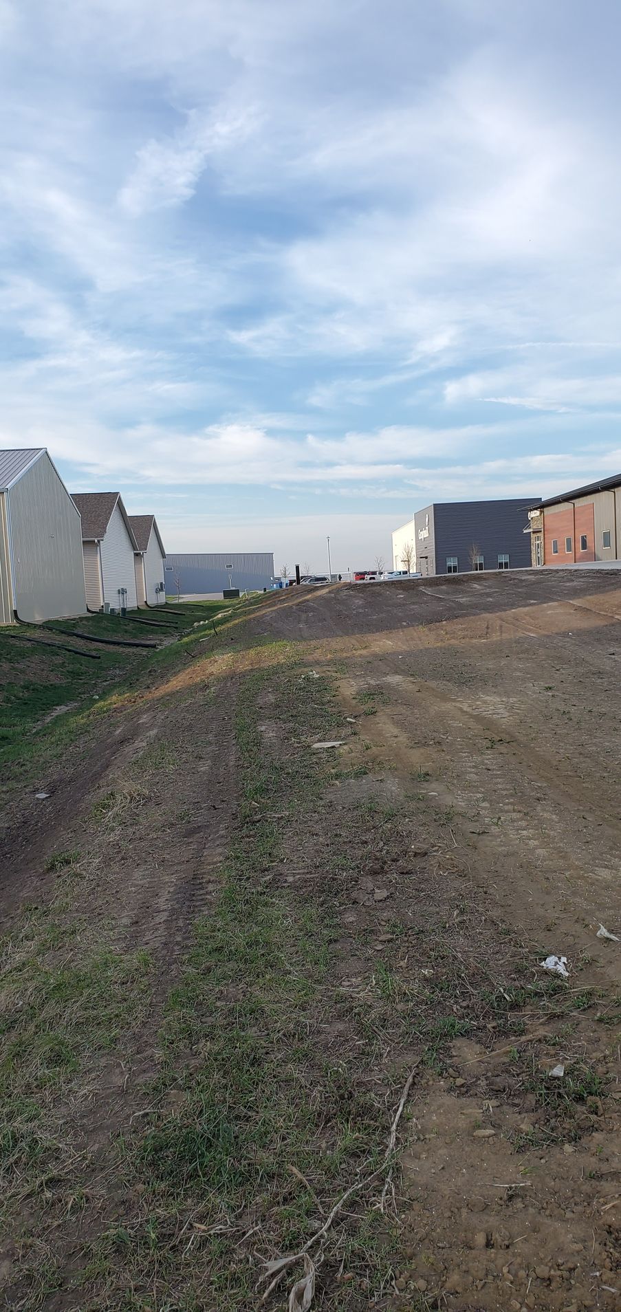 Dirt path with buildings in the background under a cloudy sky.