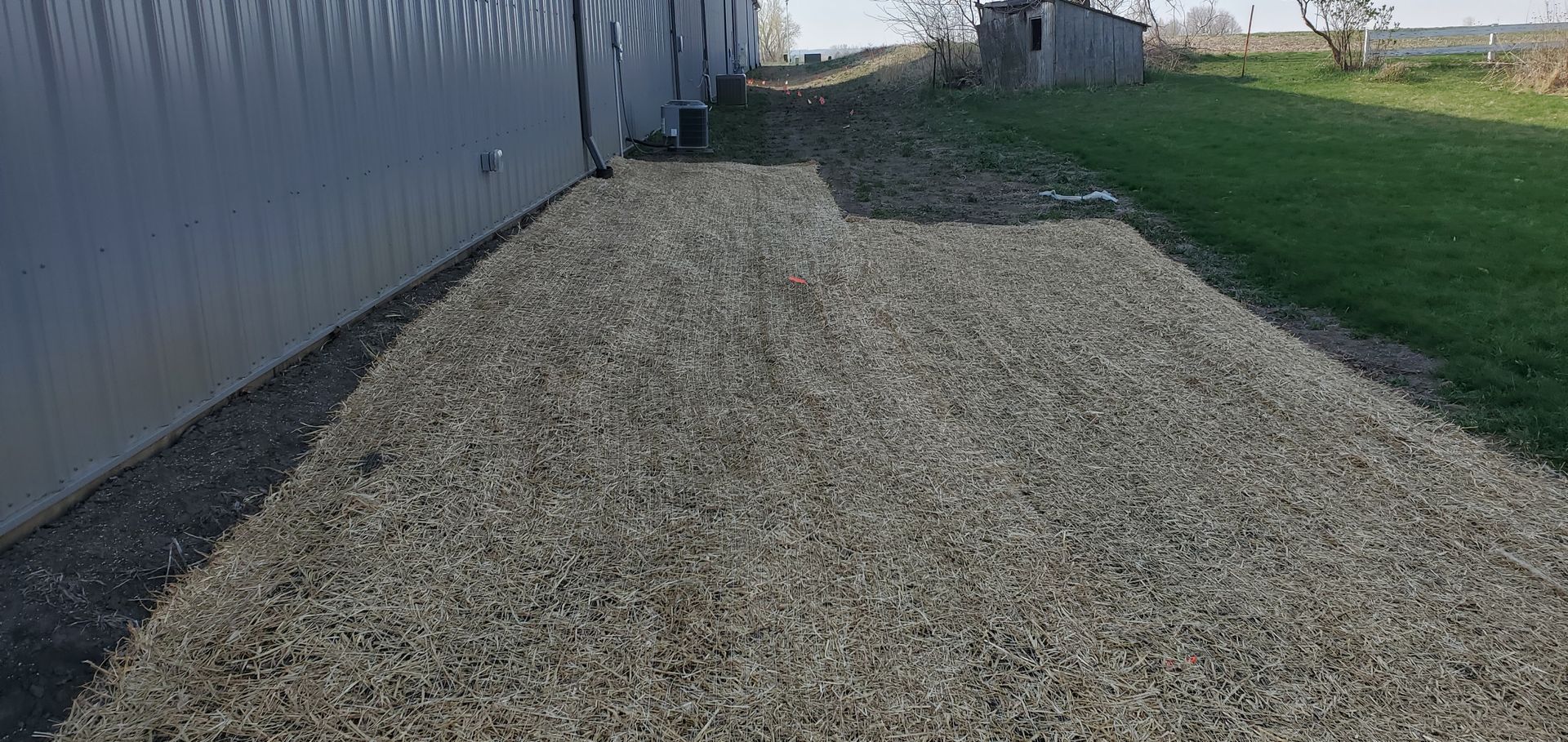Gravel path next to a building, leading to an area of grass in an outdoor setting.