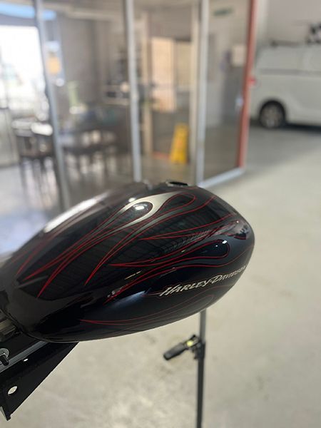 A Black and Red Motorcycle Tank Is Sitting on A Stand in A Garage — Dent Motive in Nerang, QLD