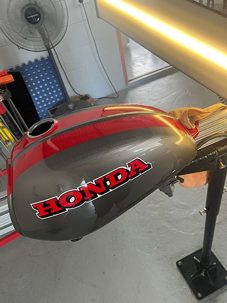A Red Honda Motorcycle Is Sitting on A Stand — Dent Motive in Nerang, QLD