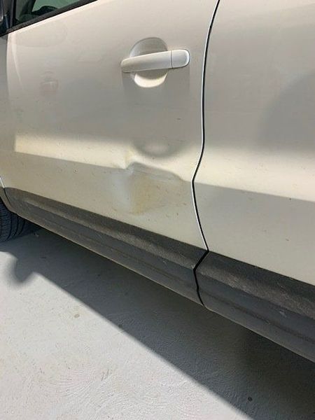 A White Car with A Damaged Door Is Parked in A Garage — Dent Motive in Nerang, QLD