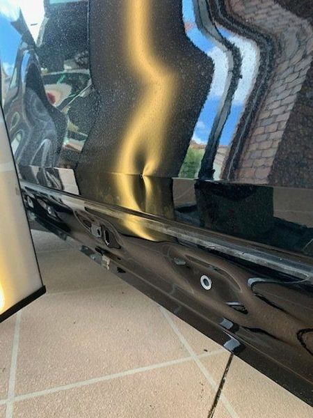 A Black Car with A Dent in The Door Is Sitting on A Tiled Floor — Dent Motive in Nerang, QLD