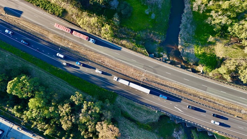 Aerial View of a Highway With Traffic, a River, and Green Trees — Dent Motive in Logan, QLD