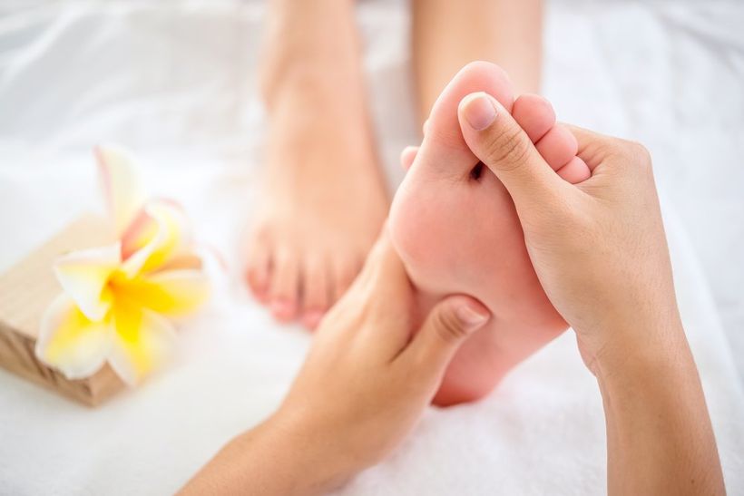 Professional therapist giving relaxing reflexology foot massage to a woman in spa