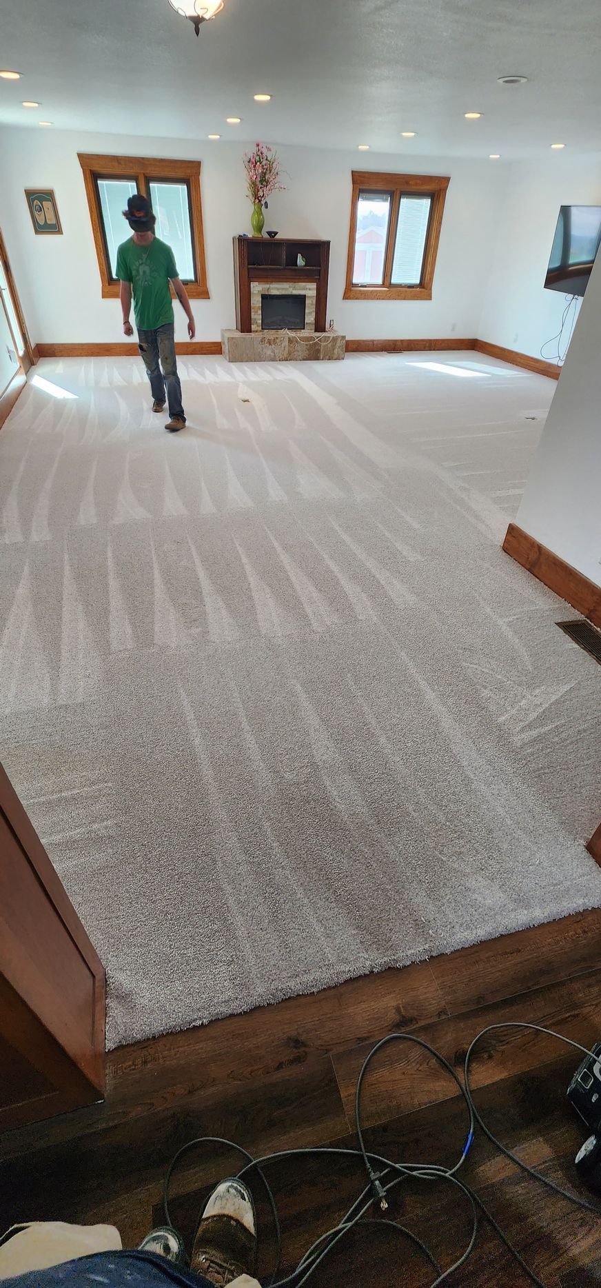 A man is standing on a large carpeted floor in a living room.