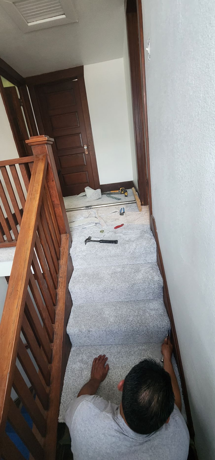 A man is laying on the floor in a hallway next to a wooden railing.