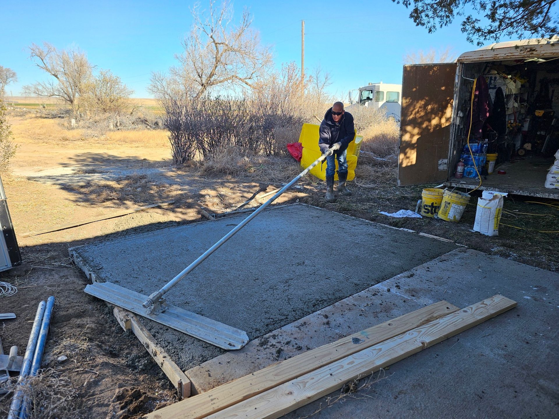 A man is digging in a pile of concrete with a shovel.