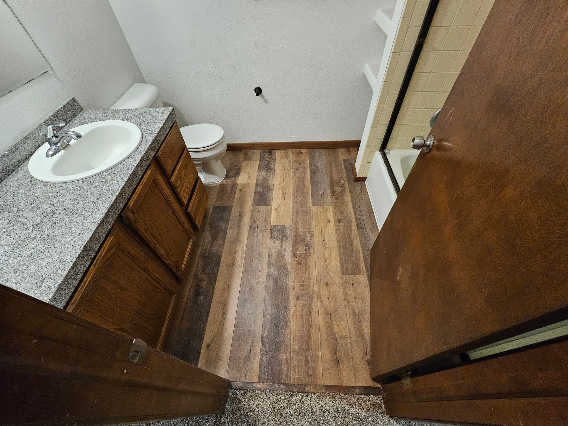 An empty room with hardwood floors and sliding glass doors.