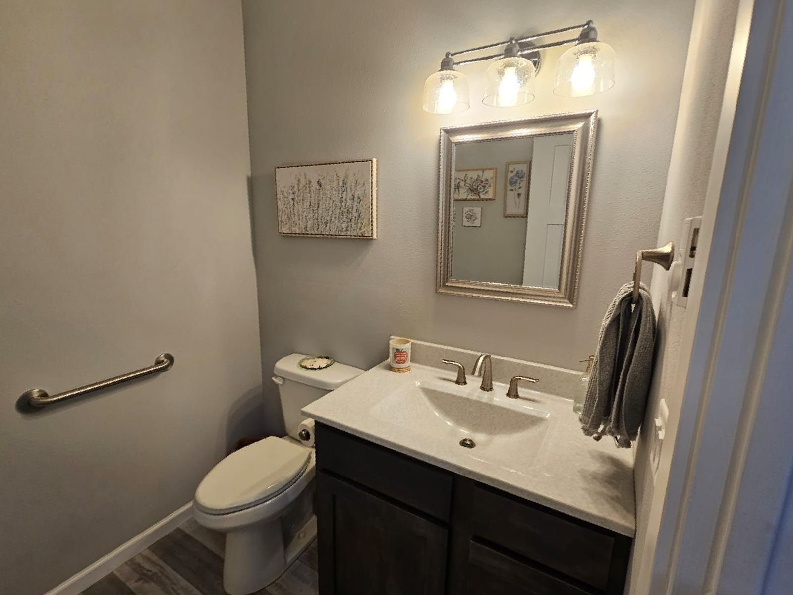 A bathroom with a toilet , sink and mirror.
