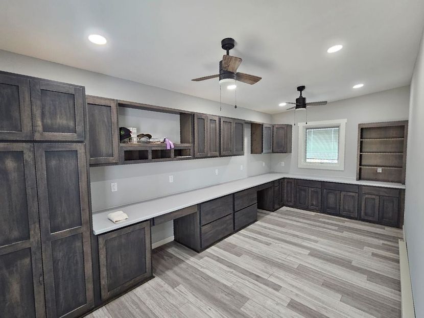 A large room with a lot of cabinets and a ceiling fan.