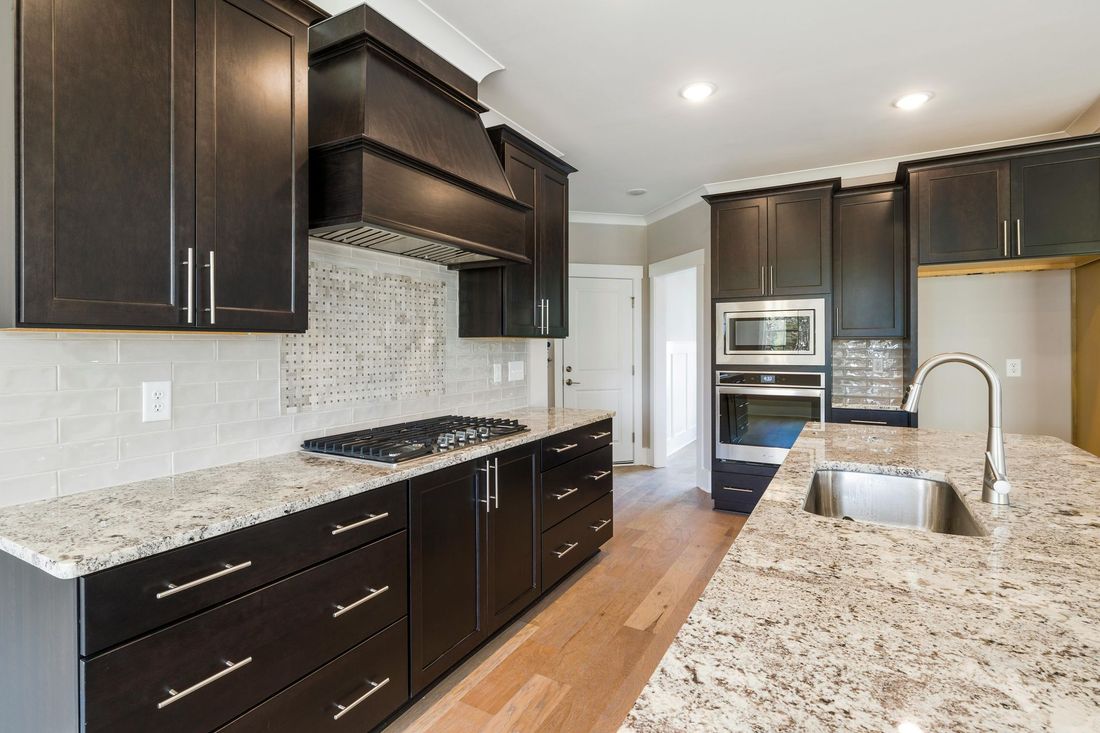 A kitchen with granite counter tops and black cabinets.