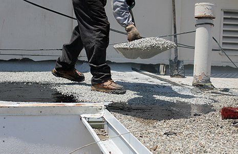 Workers use tar, gravel on a flat roof