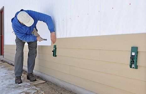 Man installing fibrous cement siding using siding gauges