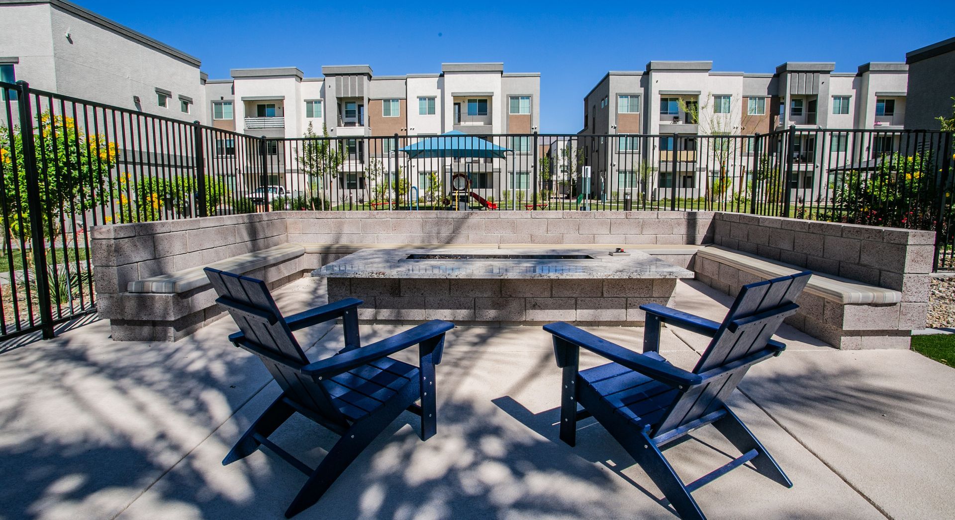 Two blue chairs are sitting in front of a fire pit.