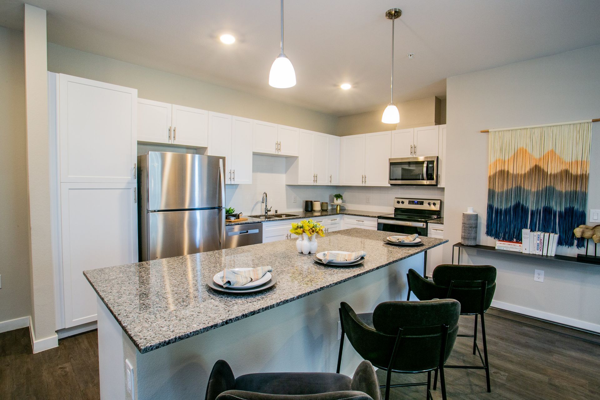 A kitchen with granite counter tops , stainless steel appliances , and white cabinets.