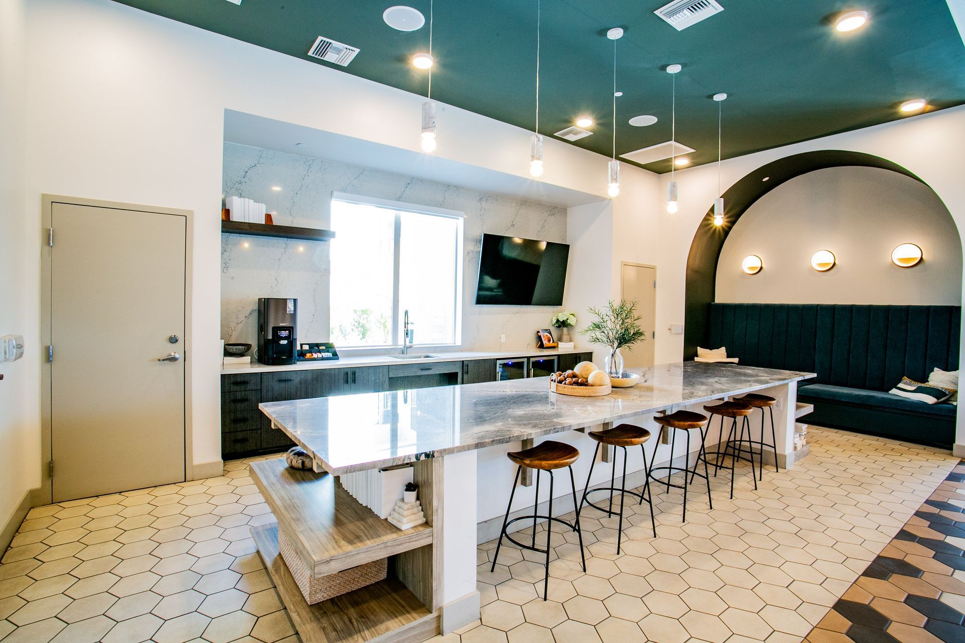 A kitchen with a large island and stools in a building.